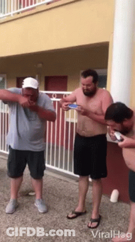 Men Standing In Front Of Building On Phones GIF