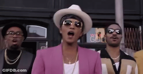 Men Standing In Front Of Building, One In Pink Jacket And Hat GIF