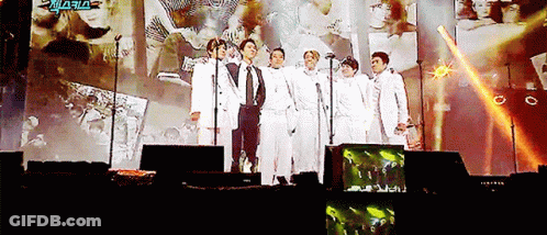 Men Standing On Stage With Microphones In Front Of Screen Saying Aria GIF