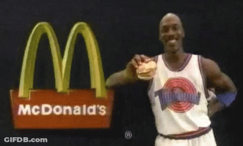 Michael Jordan Holding Hamburger In Front Of McDonald's Logo GIF