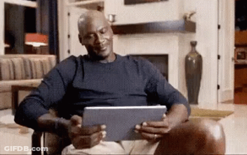 Michael Jordan Is Sitting In A Chair Looking At A Tablet Computer . GIF