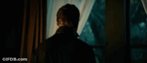 Michael Myers Is Standing In Front Of A Window In A Dark Room . GIF
