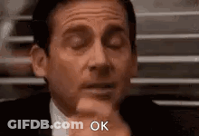 Michael Scott From The Office Is Making A Funny Face With His Eyes Closed And A Hand On His Chin . GIF
