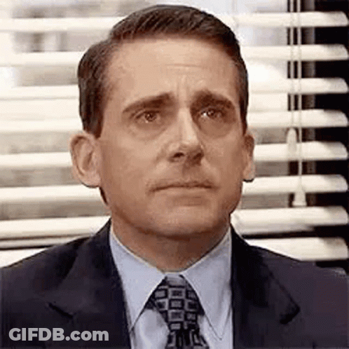 Michael Scott From The Office Is Wearing A Suit And Tie And Looking At The Camera . GIF