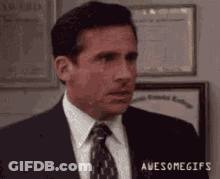 Michael Scott From The Office Is Wearing A Suit And Tie And Making A Funny Face . GIF