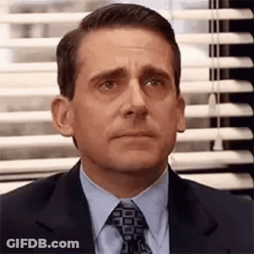 Michael Scott Is Wearing A Suit And Tie And Looking At The Camera . GIF