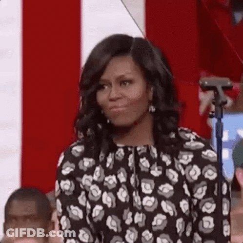 Michelle Obama Is Standing In Front Of A Microphone In Front Of A Crowd . GIF