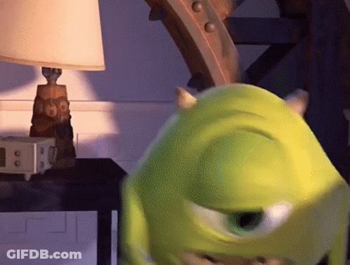 Mike Wazowski From Monsters Inc Is Standing In Front Of A Lamp On A Table GIF