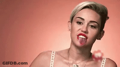 Miley Cyrus Is Sticking Her Tongue Out While Holding A Lollipop . GIF