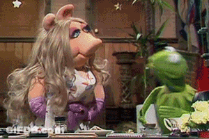 Miss Piggy And Kermit The Frog Are Sitting At A Table In A Kitchen . GIF