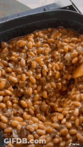 Monkey Sitting On Counter Eating Green Beans While Person Cuts Them GIF