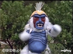 Monkey With Blue Face And White Fur Standing In Front Of Trees GIF