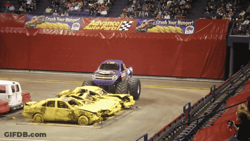 Monster Truck Driving Through Wrecked Cars At Advance Auto Parts GIF