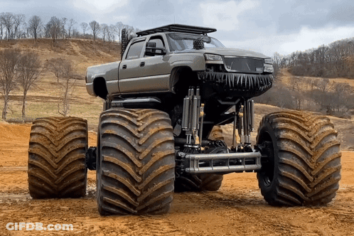 Monster Truck With Huge Tires Parked In Dirt Field GIF