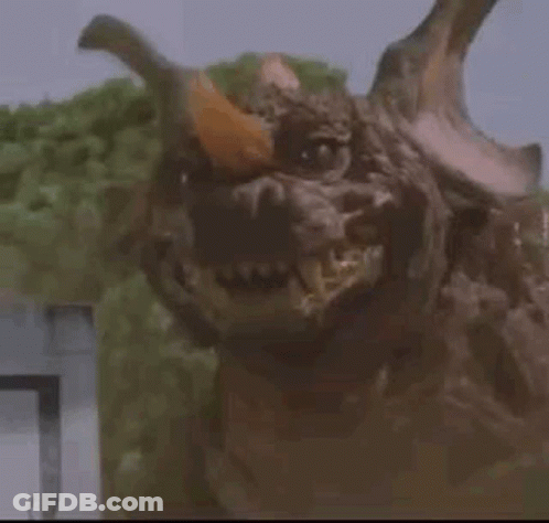 Monster With Horns Looking At Camera In Trees GIF