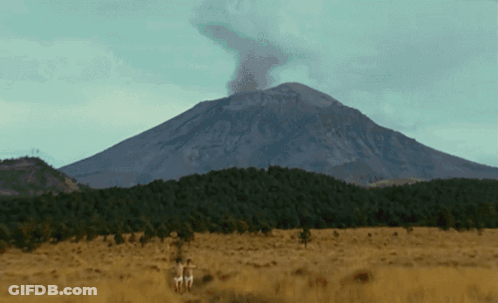 Mountain With Smoke Surrounded By Trees And Grass GIF
