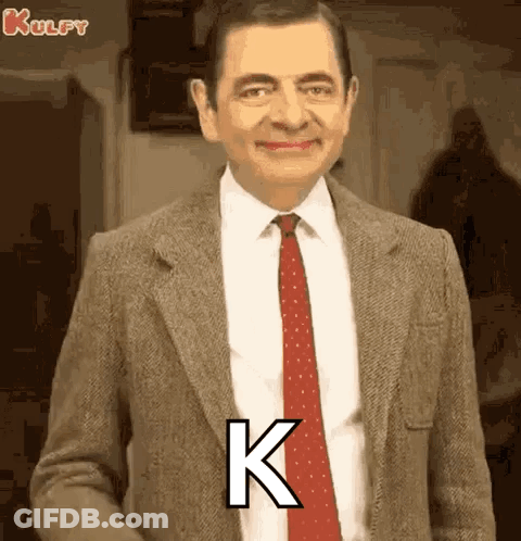 Mr Bean In Suit And Tie With Letter K On Chest GIF