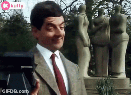 Mr Bean Is Making A Funny Face While Standing In Front Of A Camera . GIF
