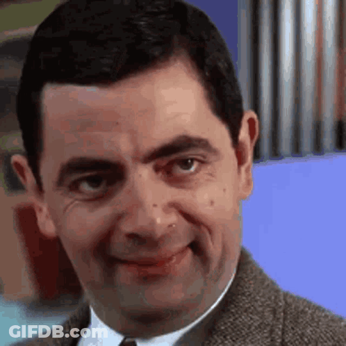 Mr Bean Is Making A Funny Face While Wearing A Suit And Tie . GIF