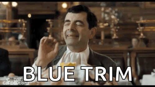 Mr Bean Is Sitting At A Table With A Napkin Around His Neck And Eating A Sandwich . GIF