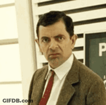 Mr Bean Is Wearing A Suit And Tie And Is Looking At The Camera . GIF