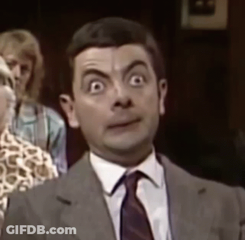 Mr Bean Is Wearing A Suit And Tie And Is Making A Funny Face . GIF