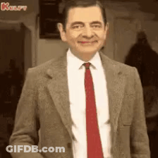 Mr Bean Is Wearing A Suit And Tie And Smiling At The Camera . GIF