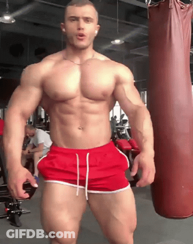 Muscular Man In Red Shorts Next To Punching Bag GIF