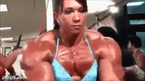 Muscular Woman In Blue Bikini Looking In Mirror At Gym GIF