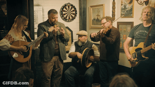 Musicians Playing In Room With Dart Board GIF
