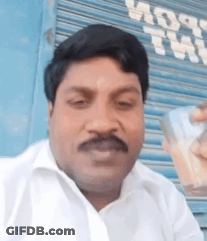 Mustached Man Holding Cell Phone By Blue Garage Door GIF