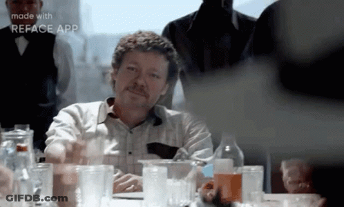 Mustached Man Sitting At Table With Glasses GIF
