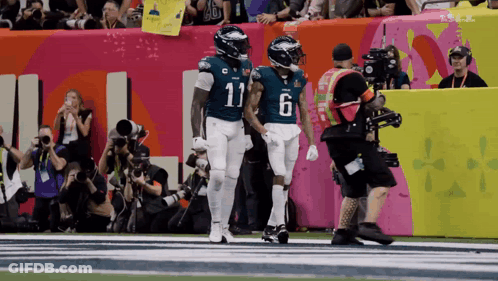 Number 11 Football Player Holding Hands With Teammate GIF