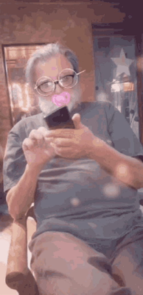 Old Man Browsing Phone With Filter GIF