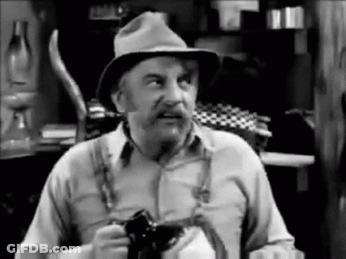 Old Man In Hat And Suspenders Holding Camera GIF