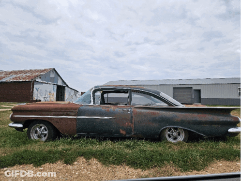 Old Rusty Car Parked In Field With Barn GIF