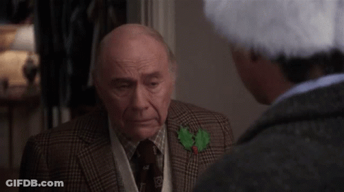 Older Man In Suit Talking To Man In Santa Hat GIF