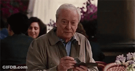 Older Man Sitting At Restaurant Holding Wallet GIF