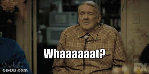 Older Man Sitting In Front Of Whataaaat Sign GIF