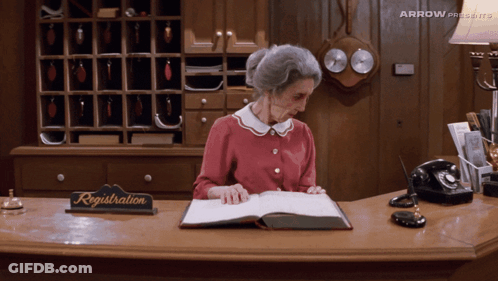Older Woman At Reception Desk With Registration Sign GIF