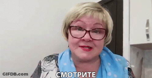 Older Woman In Glasses And Blue Scarf Talking In Kitchen GIF