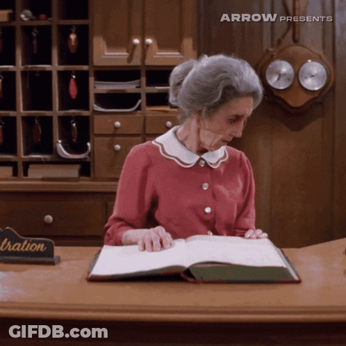 Older Woman Reading Book At Registration Desk GIF