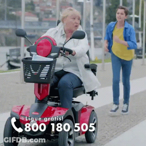 Older Woman Riding Scooter With Number 800 180 505 GIF