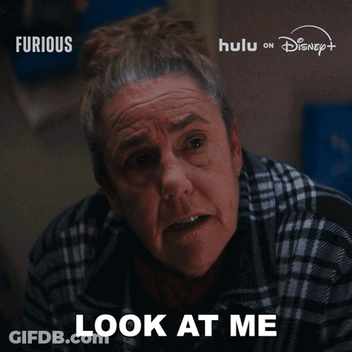 Older Woman Saying Look At Me In Front Of Furious Sign GIF