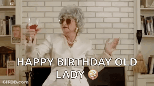 Older Woman Sitting By Fireplace Holding Wine Saying Happy Birthday Old Lady GIF