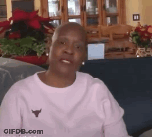 Older Woman Sitting On Couch In Pink Bull Shirt GIF
