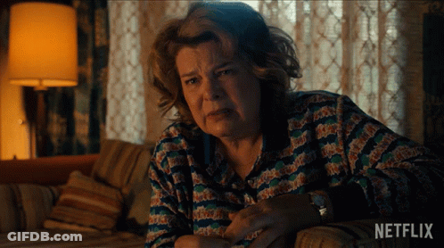Older Woman Sitting On Couch With Netflix Logo GIF