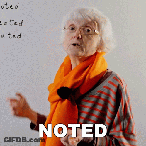 Older Woman With Glasses And Orange Scarf By Noted Board GIF