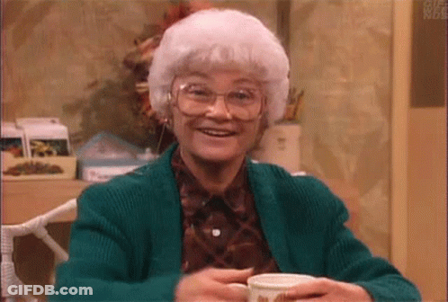 Older Woman With White Hair And Glasses Smiling Holding Coffee GIF