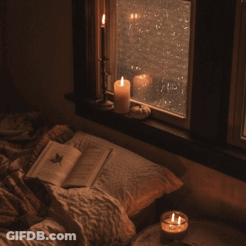 Open Book On Bed Next To Candle GIF